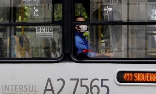 homem dentro de ônibus público com janela aberta e máscara