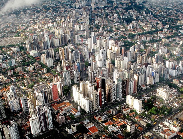 <p>foto aérea de Curitiba mostrando prédios altos no entorno de via com transporte coletivo de massa</p>