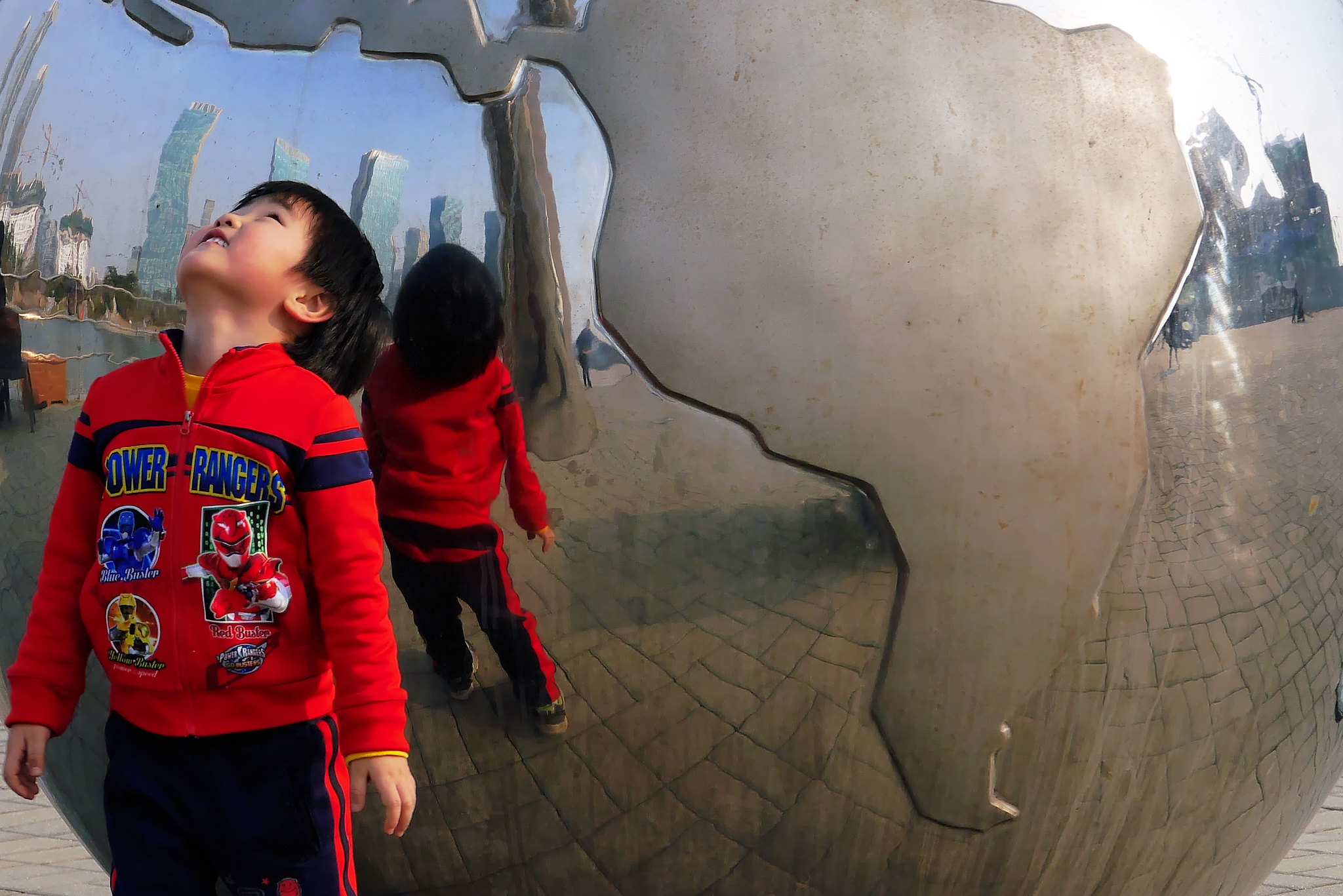 <p>criança olha para cima de roupa vermelha em cidade da Coréia do Sul</p>